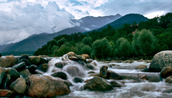 A river with mountains in the background in Jammu and Kashmir (Saqib Majeed/SOPA Images/Shutterstock)