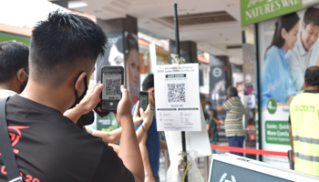 Man scans a QR code of a digital check-in system in Singapore to control the spread of COVID-19 (YK Chan/AP/Shutterstock)