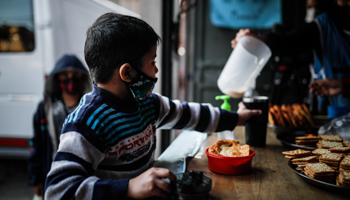 A child waiting for a glass of milk at a soup kitchen in Buenos Aires (Juan Ignacio Roncoroni/EPA-EFE/Shutterstock)