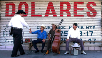 Musicians greet each other under a sign that reads "dollars", Monterrey, Mexico (Gregory Bull/AP/Shutterstock)