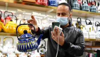 A Yemeni trader selects Chinese tea pots in Zhejiang Province while communicating with his Saudi client via video link (Xinhua/Shutterstock)