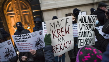 Church ‘defenders’ face anti-paedophilia protesters with a placard (centre) saying “You have blood on your hands” outside a church in Warsaw, December 19, 2020 (Attila Husejnow/SOPA Images/Shutterstock)