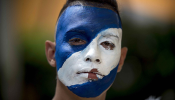A young man with his face painted in the colours of the Nicaraguan flag participates in a march in Managua, Nicaragua, October 2020 (Agencia EFE/Shutterstock)