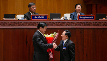 Thongloun Sisoulith (left), Lao People’s Revolutionary Party general secretary and state president, shaking hands with Phankham Viphavanh (right), prime minister (Xinhua/Shutterstock)