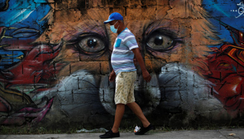 A man wearing a mask walks by a mural in Panama City, June, 2020 (Bienvenido Velasco/EPA-EFE/Shutterstock)