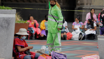 A cleaning worker approaches a woman selling her handicrafts in Mexico City's Zócalo, 20 March (Gerardo Vieyra/NurPhoto/Shutterstock)