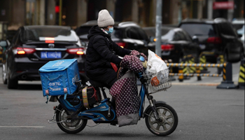 Food delivery worker rides on a street in Beijing, January 2021 (Andy Wong/AP/Shutterstock)