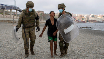 Spanish soldiers escort a migrant at his arrival in Ceuta, Spain, May 19 (Brais Lorenzo/EPA-EFE/Shutterstock)
