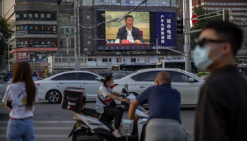 People at a crossing in Hong Kong where a large video screen shows Chinese President Xi Jinping speaking in Beijing (Mark Schiefelbein/AP/Shutterstock)