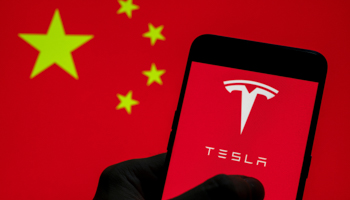 Tesla logo seen on an Android mobile device with the Chinese flag in the background (Budrul Chukrut/SOPA Images/Shutterstock)