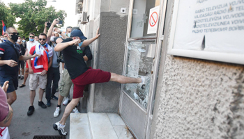 Anti-government protesters smash the glass door of Radio Television of Vojvodina during a demonstration against the state’s handling of the COVID-19 pandemic, Novi Sad, July 8 (Dragan Gojic/BETAPHOTO/SIPA/Shutterstock)