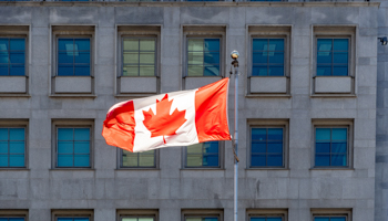 The Canadian flag is reflected against a pattern of windows in the downtown district of Toronto, Canada (Roberto Machado Noa/Shutterstock)