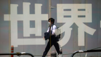 A man is reflected in window of a shop in Tokyo (Eugene Hoshiko/AP/Shutterstock)