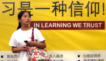 A woman walks past a billboard advertising private tutoring (Stephen Shaver/UPI/Shutterstock)