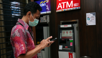 A customer at an ATM in Central Jakarta (Kuncoro Widyo Rumpoko/Pacific Press/Shutterstock)