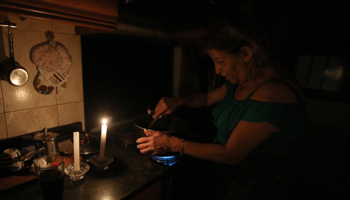 A woman prepares a meal by candlelight, Beirut, September (Nabil Mounzer/EPA-EFE/Shutterstock)