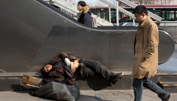 A homeless man sleeps on the street in Beijing (Ng Han Guan/AP/Shutterstock)