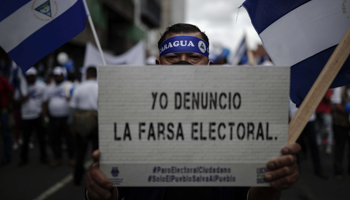 A Nicaraguan protester holds a sign denouncing his country’s elections as a “farce”, during demonstrations in neighbouring Costa Rica. San Jose, November 7, 2021 (Jeffrey Arguedas/EPA-EFE/Shutterstock)
