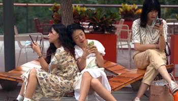 Chinese women using their smartphones in Beijing, July 30, 2021 (Stephen Shaver/UPI/Shutterstock)