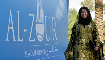 A woman passes a sign for Al-Zour oil refinery in Kuwait (Raed Qutena/EPA/Shutterstock)