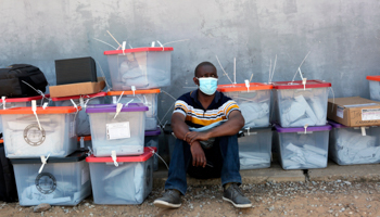 Polling agent sits next to ballot boxes during Zambia's recent election (Tsvangirayi Mukwazhi/AP/Shutterstock)