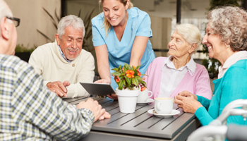 Caregiver with tablet pc and a group of seniors in retirement home (Shutterstock / Robert Kneschke)