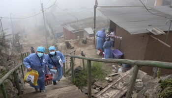 Health workers delivering doses of Pfizer vaccine in a shantytown on the outskirts of Lima (Guadalupe Pardo/AP/Shutterstock)