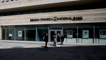 A customer wearing a protective mask queues with others outside a
branch of National Bank of Greece, Athens, March 19, 2020 (Kostas Tsironis/EPA-EFE/Shutterstock)