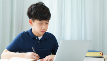 An Asian teenage student attending a virtual classroom (Shutterstock / myboys.me)