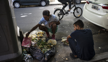 People scavenging food from the rubbish outside a restaurant in Buenos Aires (Rodrigo Abd/AP/Shutterstock)