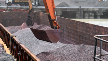 Crane lifting iron ore from a barge (Shutterstock / creativevikas)