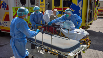 Medical staff in Hong Kong move a COVID-19 patient from an ambulance to a stretcher (Emmanuel Serna/SOPA Images/Shutterstock)