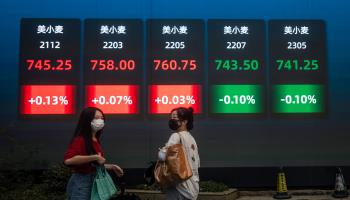 People walk in front of a screen showing stock exchange and economic data in Shanghai (Alex Plavevski/EPA-EFE/Shutterstock)