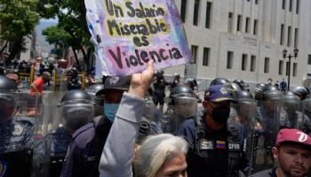 A protester in Caracas with a placard reading "A miserable salary is violence" (Ariana Cubillos/AP/Shutterstock)