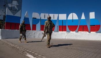 Russian soldiers in occupied Mariupol near a large sign showing the city's name, repainted in the colours of the Russian flag (Sergei Ilnitsky/EPA-EFE/Shutterstock) 