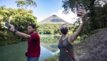 Tourists take selfies in front of the Arenal volcano. Costa Rica, August 2020 (Jeffrey Arguedas/EPA-EFE/Shutterstock)