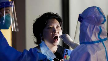 A woman takes mandatory PCR test on the street in Shanghai (Alex Plavevski/EPA-EFE/Shutterstock)