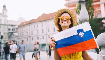 Tourists, one holding Slovenian flag, on central square of the capital, Ljubljana, no date (Natalia Deriabina, Shutterstock). 