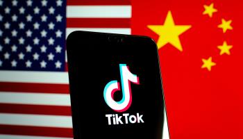 The TikTok app logo on a smartphone screen with the flags of the United States and China (AP/Shutterstock)