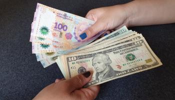 Argentine pesos being exchanged for US dollars (Shutterstock)