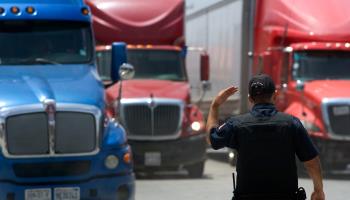 A policeman directs lorries as they wait in line to enter a commercial border inspection station. Tijuana, Mexico, June 2019. (David Maung/EPA-EFE/Shutterstock)