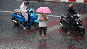A pedestrian tries to shield himself from heavy rain during a thunderstorm in Bangkok, Thailand. April 24, 2023. (RUNGROJ YONGRIT/EPA-EFE/Shutterstock)
