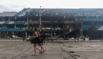 A couple walk past a damaged terminal of the Ukrainian Danube Shipping Company in Izmail after a Russian drone strike close to the border with Romania, August 2 (Igor Tkachenkov/EPA-EFE/Shutterstock)