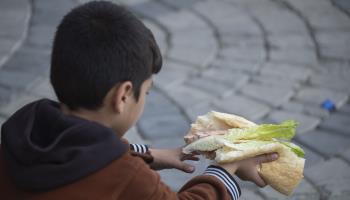 Afghan refugee holding a donated meal, Tehran, October 8, 2023 (Morteza Nikoubazl/NurPhoto/Shutterstock)