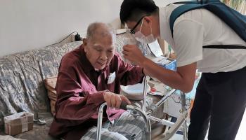 A care manager talks to an elderly man at his home in Beijing (Xinhua/Shutterstock)