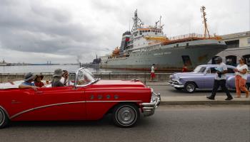 A vintage car drives past a Russian war frigate in Havana, June 2024 (Shutterstock)