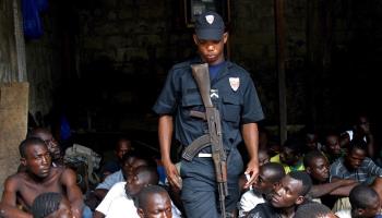 Ivorian policeman walks amid suspected drug dealers in 2007 operation (Legnan Koula/EPA/Shutterstock)
