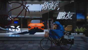 A woman rides her bicycle past a Chinese XPeng electric vehicle shop in Shanghai (ALEX PLAVEVSKI/EPA-EFE/Shutterstock)