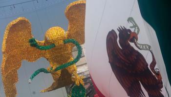 The Mexican flag flies next to an eagle and snake statue erected ahead of Independence Day celebrations in Mexico City. September 2024 (Gerardo Vieyra/NurPhoto/Shutterstock)