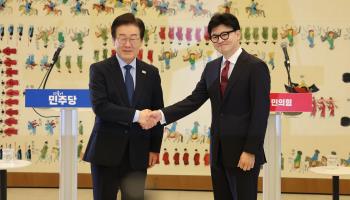 Ruling People Power Party leader Han Dong-hoon (right) shakes hands with main opposition Democratic Party of Korea leader Lee Jae-myung (left) (YONHAP/EPA-EFE/Shutterstock)